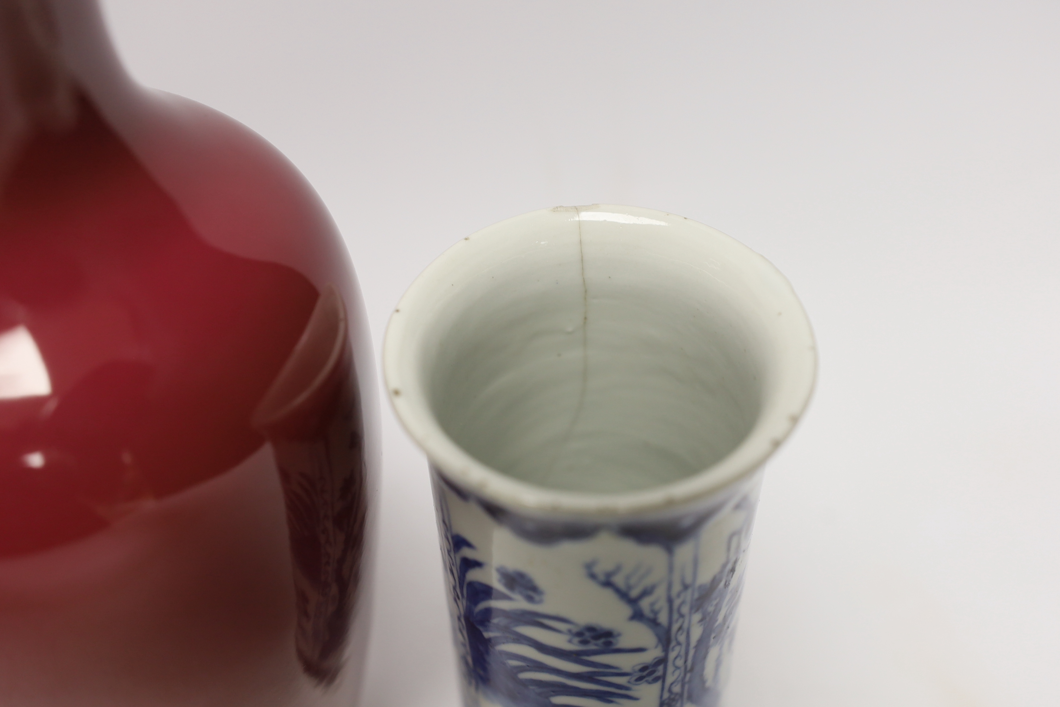 An early 20th century Chinese blue and white cylindrical vase, a ruby ground vase and an enamelled porcelain double lozenge vase, largest 24cm high (3)